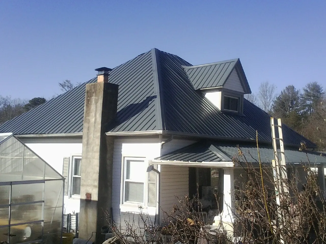 Dark blue standing seam metal roof on a white farmhouse with dormer — Slate & Tile Roof Repair by Roofing Brothers in Casstown