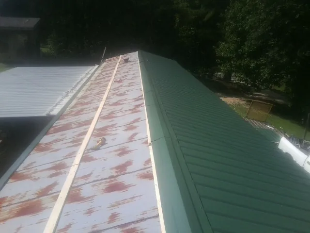 Old rusted panels beside newly installed green metal roofing — Wind Damage Roof Repair by Roofing Brothers in Casstown