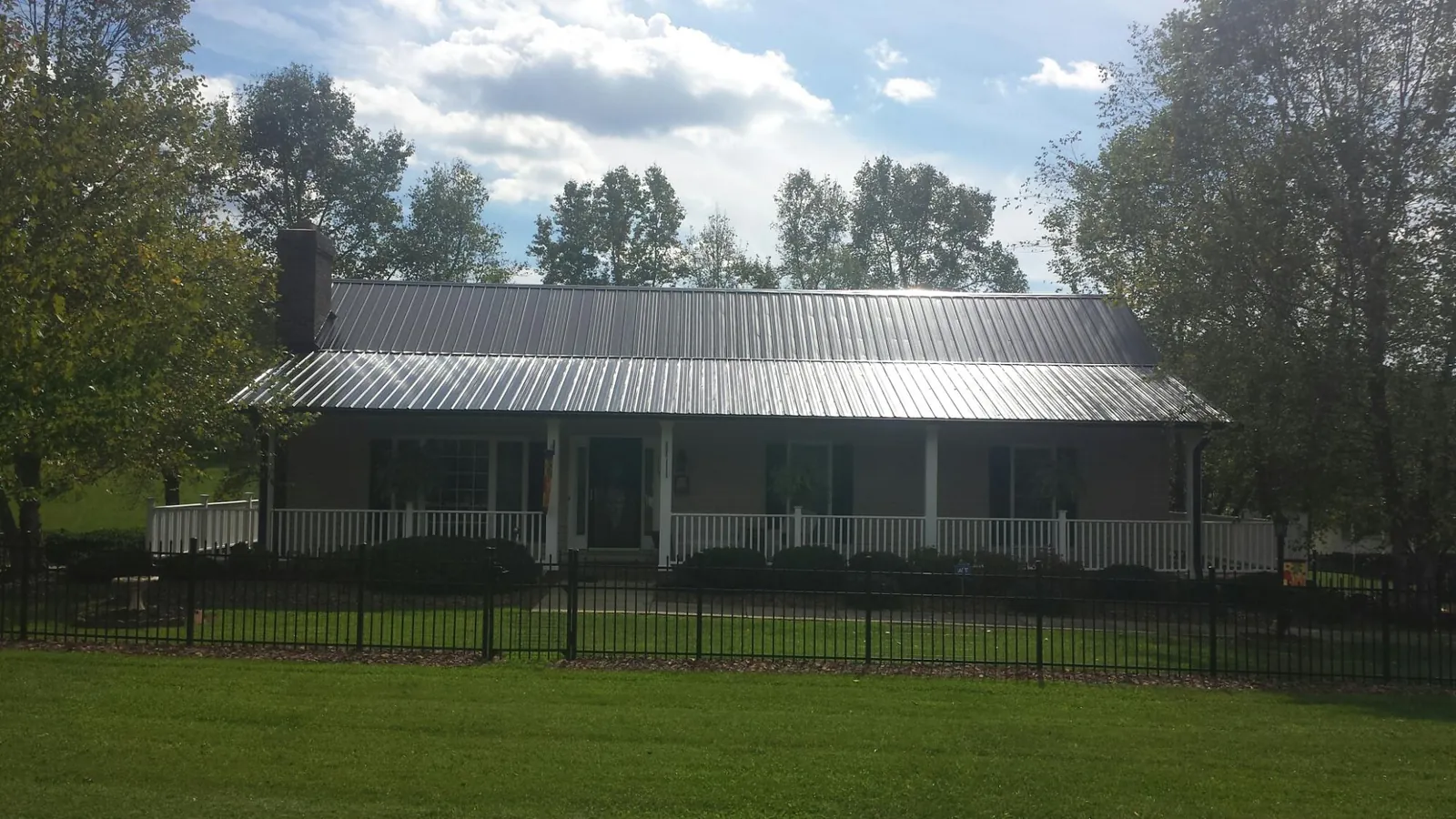 Gray metal roof on a brick ranch with a full width front porch — Gutter Guard Installation work by our crew in Casstown