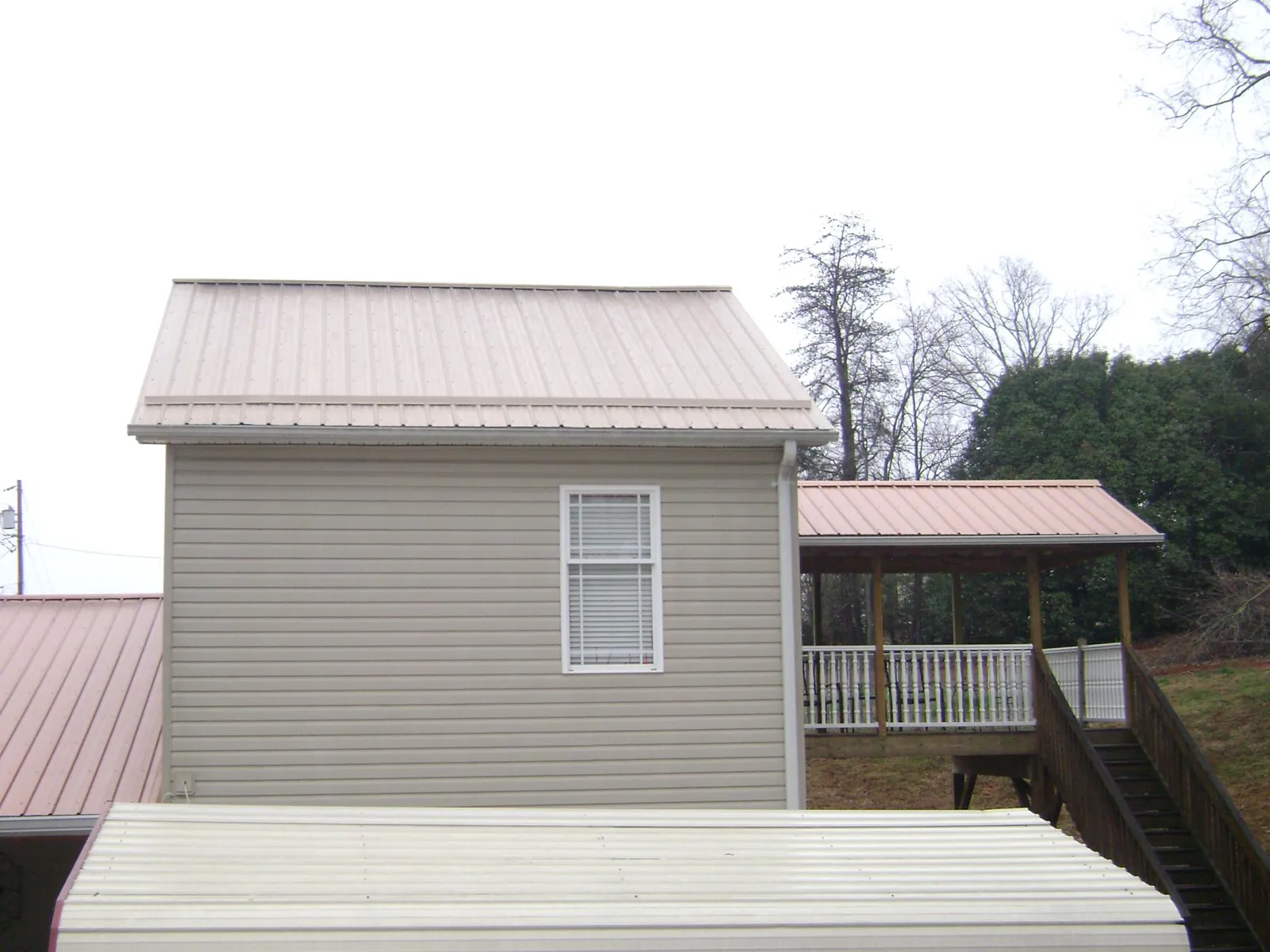 Tan metal roofs on a two story addition and attached porch, from a Roof Replacement job in Casstown