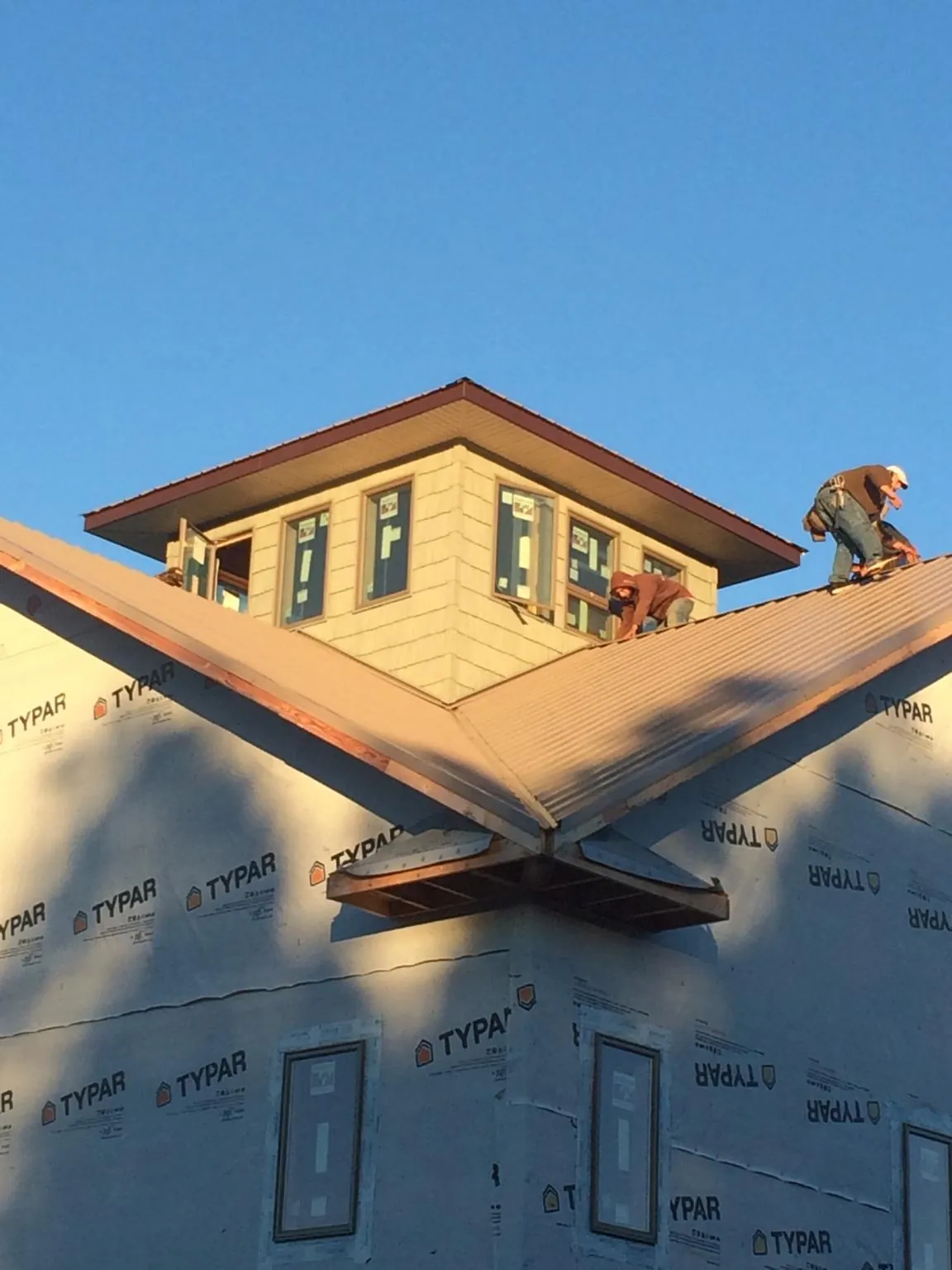 Roofers working around a rooftop cupola on a new metal roof at sunset — Roof Waterproofing in Casstown by Roofing Brothers